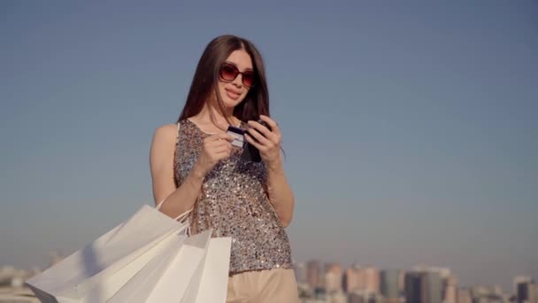 Ευτυχισμένες πολυτελείς γυναίκες που κατέχουν πιστωτική κάρτα και τσάντες για ψώνια - Πλάνα, βίντεο