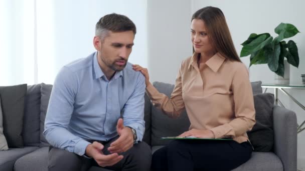 Triste patient homme parlant de son problème avec la psychologue femme qui le soutient - Séquence, vidéo