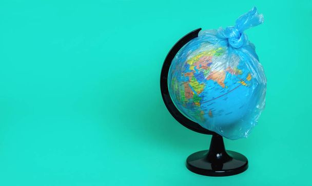Globe in a plastic bag on a blue background. Global warming. Waste sorting. Cleansing and protecting the planet. Copy space. Concept - Foto, Bild