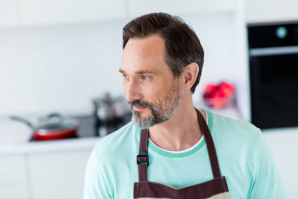 Photo of pretty dreamy age man dressed blue t-shirt apron smiling indoors home room - Photo, image
