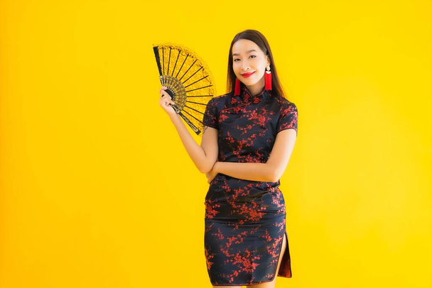 Портрет красива молода азіатка носить китайську сукню з вентилятором для китайської концепції нового року на жовтому ізольованому фоні
 - Фото, зображення