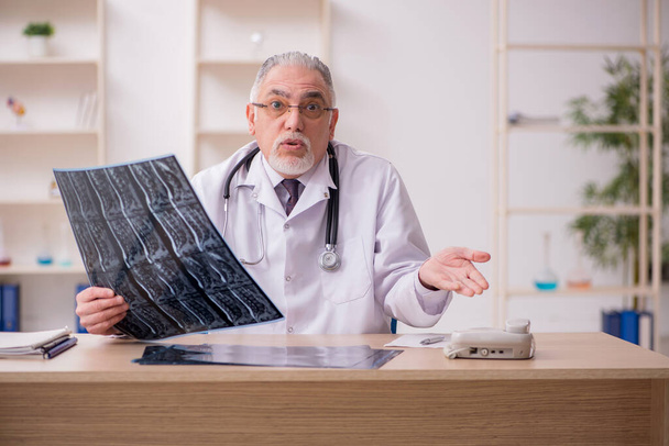 Παλαιός άνδρας ακτινολόγος ιατρός που εργάζεται στην κλινική κατά τη διάρκεια πανδημίας - Φωτογραφία, εικόνα
