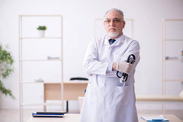 Old male doctor working in the clinic - Foto, Bild
