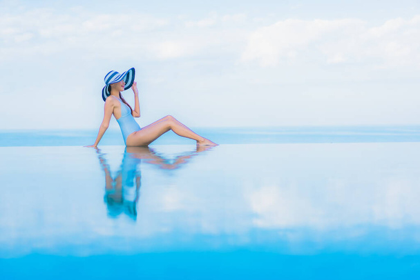 Retrato hermosa joven mujer asiática relajarse sonrisa alrededor de la piscina al aire libre en el complejo hotelero casi mar playa océano - Foto, Imagen