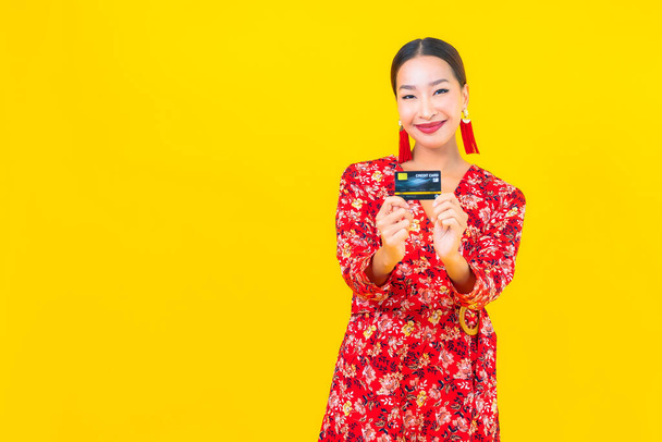 Sarı izole edilmiş arka planda alışveriş yapmak için güzel bir Asyalı kadın kredi kartı. - Fotoğraf, Görsel