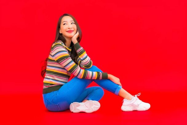 Ritratto bella giovane donna asiatica sorriso con azione su sfondo rosso isolato - Foto, immagini