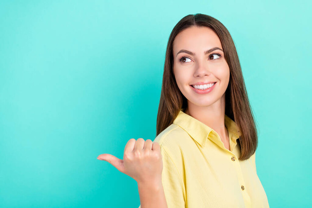 Photo of positive young dreamy woman point finger thumb look empty space idea isolated on teal color background - Foto, Imagen