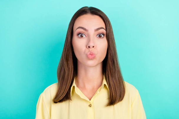 Photo of flirty young brunette lady blow kiss wear yellow blouse isolated on teal color background - Zdjęcie, obraz