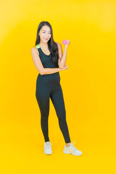 Porträt schöne junge asiatische Frau tragen Fitness-Studio-Outfit bereit für die Übung auf gelbem Hintergrund - Foto, Bild