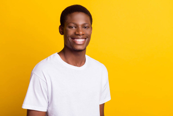 Photo of nice brunet young guy wear white t-shirt isolated on yellow color background - Zdjęcie, obraz