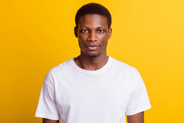 Photo of young serious dark skin man wear white casual t-shirt isolated on shine yellow color background - Fotó, kép