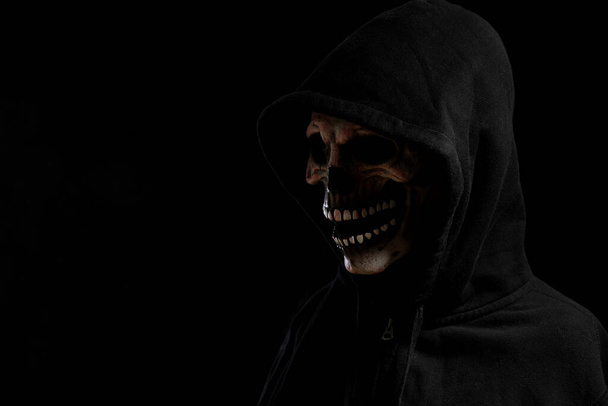 Η μάσκα κρανίο με κουκούλα πουκάμισο στο σκούρο φόντο. - Φωτογραφία, εικόνα