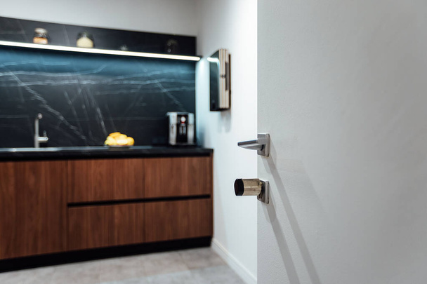 an open refrigerator door in the kitchen in a minimalist design. strict brown kitchen facade. expensive apartment interior - 写真・画像