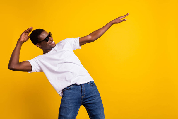 Portrait of attractive cheerful guy dancing having fun fooling isolated over bright yellow color background - Foto, Imagem
