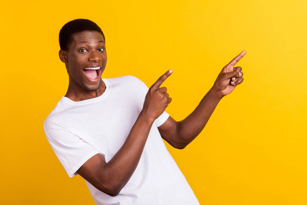 Portrait von attraktiven erstaunt fröhlichen Kerl demonstrieren Werbeangebot Schnäppchen isoliert über leuchtend gelben Farbhintergrund - Foto, Bild