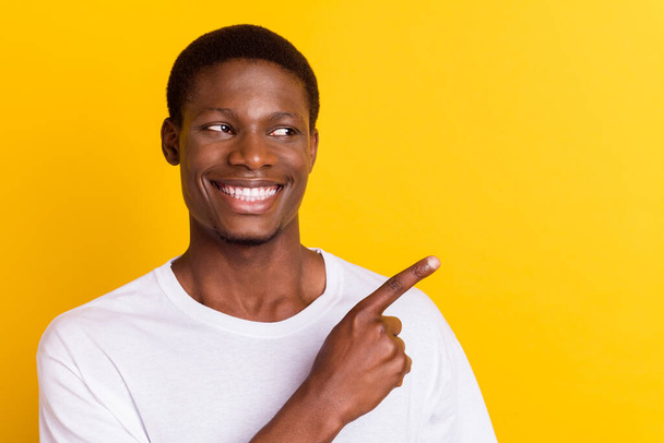 Portrait of attractive cheerful guy demonstrating ad advert new novelty isolated over bright yellow color background - Zdjęcie, obraz