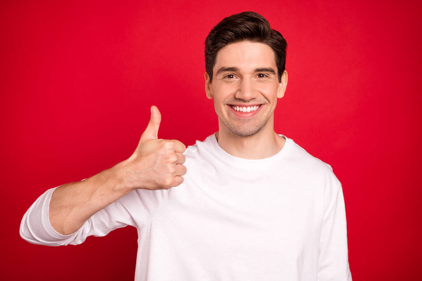 Photo of optimistic brunet young guy show thumb up wear white shirt isolated on red color background - Valokuva, kuva