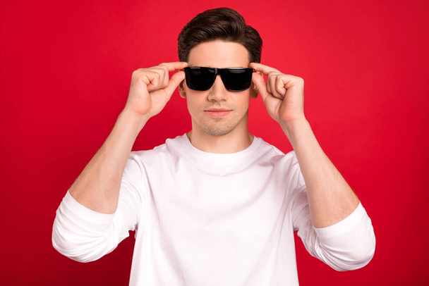 Photo portrait brunet guy in casual outfit serious wearing sunglass isolated vibrant red color background - Foto, imagen