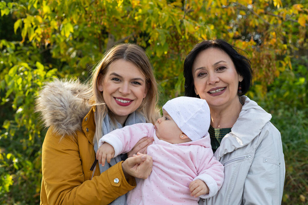 Portrait of a smiling woman with grandmother and granddaughter at the park - Foto, Bild