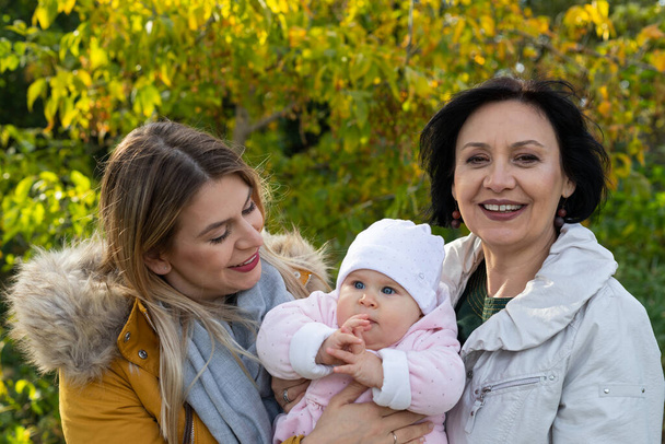 Portrait of a smiling woman with grandmother and granddaughter at the park - Photo, image