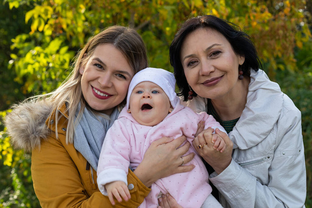 Portrait of a smiling woman with grandmother and granddaughter at the park - Φωτογραφία, εικόνα