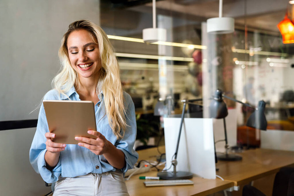 Porträt einer attraktiven jungen Geschäftsfrau, die im Büro lächelnd an einem digitalen Tablet arbeitet. Geschäftsleute-Konzept - Foto, Bild