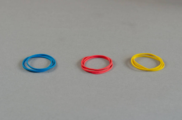 Three groups of stationery rubber bands on a gray background. Multicolored round stationery. Close-up.  Selective focus. - Photo, Image