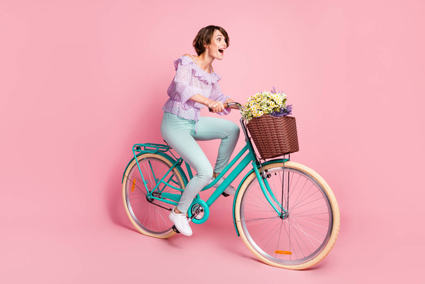 Full size profile side photo of young attractive happy excited crazy girl riding bicycle fast isolated on pink color background - Фото, зображення