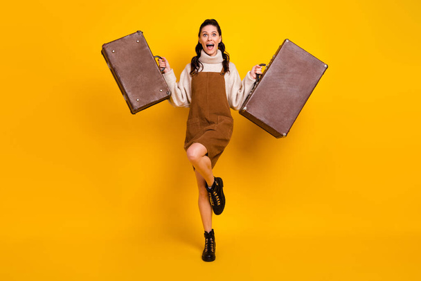 Full size photo of nice brunette optimistic curly hairdo lady hold bags wear sweater overall boots isolated on yellow background - Φωτογραφία, εικόνα