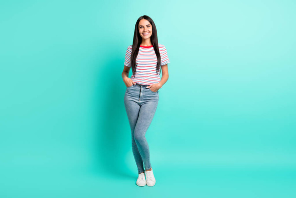 Full size photo of nice brunette optimistic long hairdo lady stand wear t-shirt jeans sneakers isolated on teal color background - Foto, Imagem