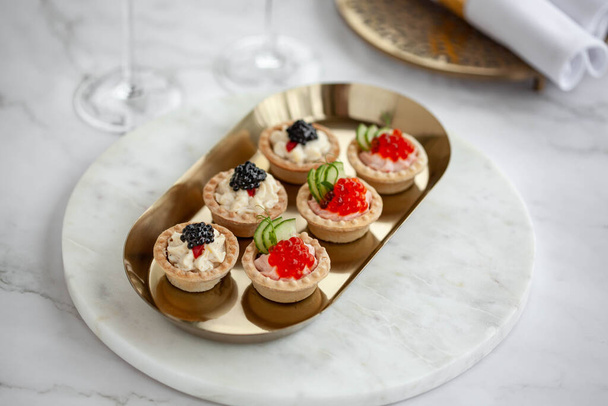Black and red caviar tartlets on gold plate - Foto, Imagem