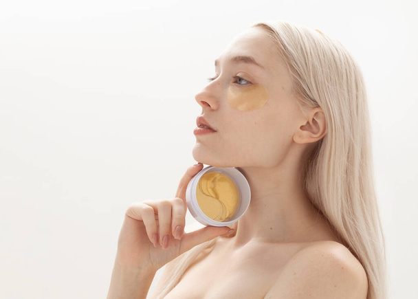 beautiful blonde with a jar of gold eye patches - Foto, Imagem