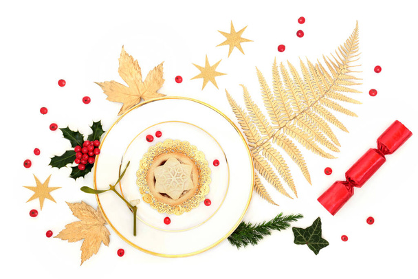 Розкішний різдвяний фарширований пиріг на тарілці з золотим листям, зірками, зимовою зеленню, крекером та вільними ягідками Холлі на білому тлі
. - Фото, зображення