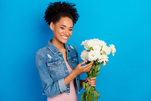 Photo of cheerful young happy afro american woman hold hands bloom flowers isolated on blue color background - Zdjęcie, obraz