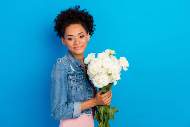 Photo of cheerful young happy afro american woman hold hands flowers good mood isolated on blue color background - Foto, Imagem
