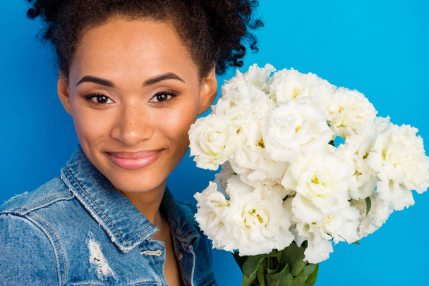 Photo of attractive nice young afro american woman hold hands flowers smile enjoy isolated on blue color background - Фото, зображення