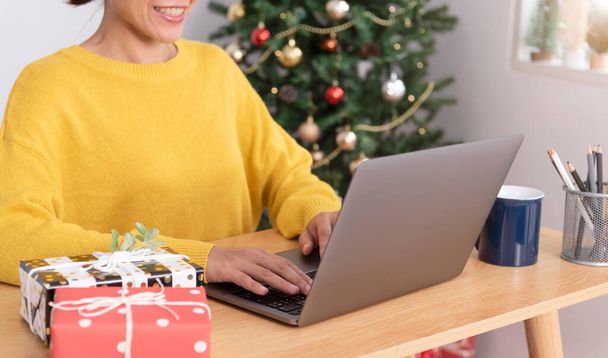 business woman working on computer in Christmas day with gift box and christmas tree background. - Foto, Bild