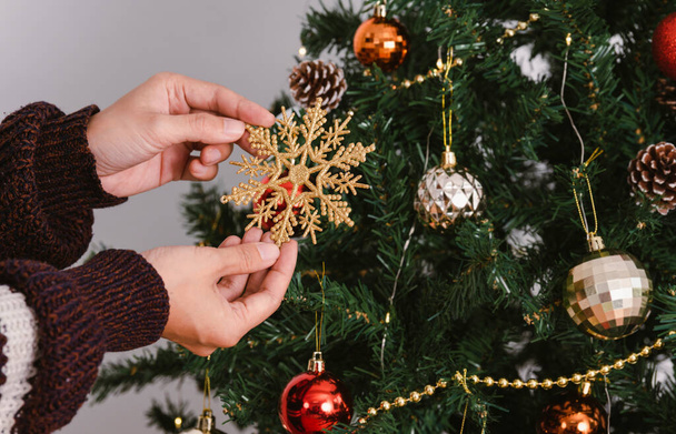 Γυναίκα διακόσμηση χριστουγεννιάτικο δέντρο με στολίδια την ημέρα των Χριστουγέννων. - Φωτογραφία, εικόνα
