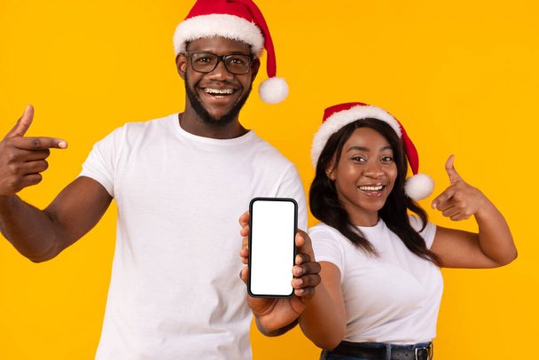 Black Couple Shooting Phone Blank Screen Advertising Christmas Offer, Studio - Фото, изображение