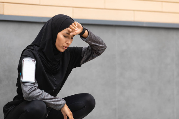 Väsynyt urheilullinen musliminainen hengästyy aktiivisen harjoittelun jälkeen ulkona - Valokuva, kuva