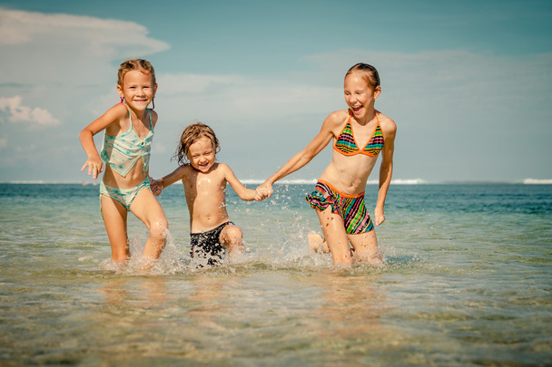 Three happy kids playing on beach at the day time - Zdjęcie, obraz