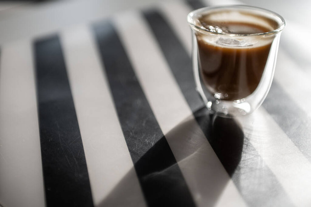 Close Up photo of cup with black coffee and shadow on black and white background - Foto, imagen