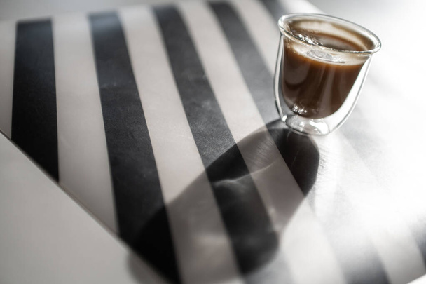 Close Up photo of cup with black coffee and shadow on black and white background - Фото, изображение