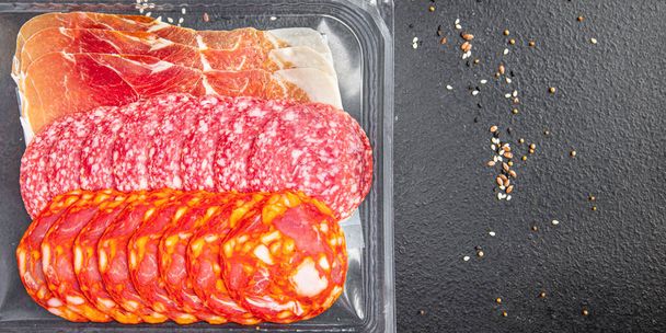 ソーセージ肉各種スライススライスサラミチョリソージャモンプロシュートテーブルの上の新鮮な食事スナックコピースペースフード背景 - 写真・画像