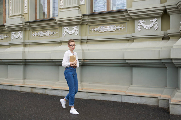 jolie femme avec des lunettes marchant autour de la ville avec une éducation de livre - Photo, image