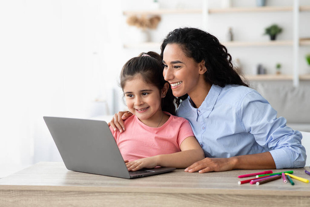 Ηλεκτρονική Εκπαίδευση. Κοριτσάκι και η όμορφη μαμά της χρησιμοποιούν φορητό υπολογιστή στο σπίτι - Φωτογραφία, εικόνα