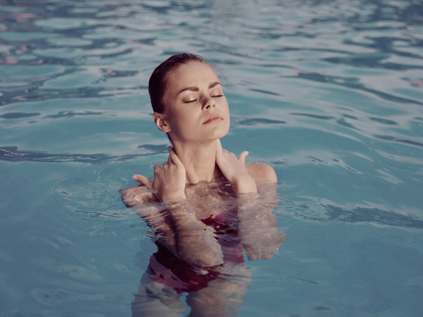 hezká žena se zavřenýma očima v plavkách v luxusním bazénu - Fotografie, Obrázek