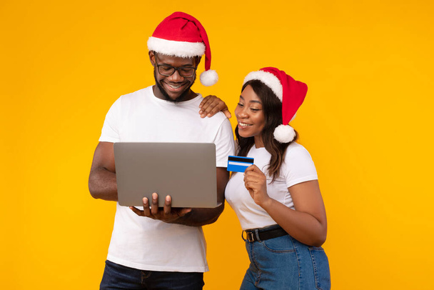 Casal preto usando laptop e cartão comprando presentes de Natal, estúdio - Foto, Imagem