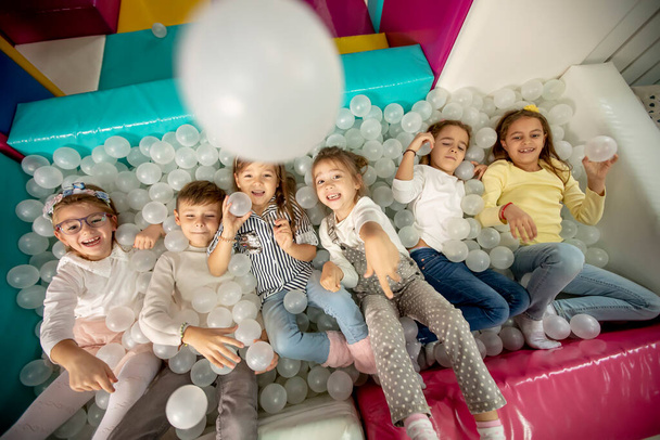 Group of happy little kids in ball pit smiling happily at camera while having fun - Valokuva, kuva