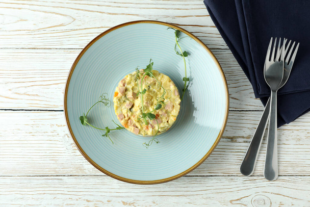 Concept van lekker eten met Olivier salade op witte houten tafel - Foto, afbeelding